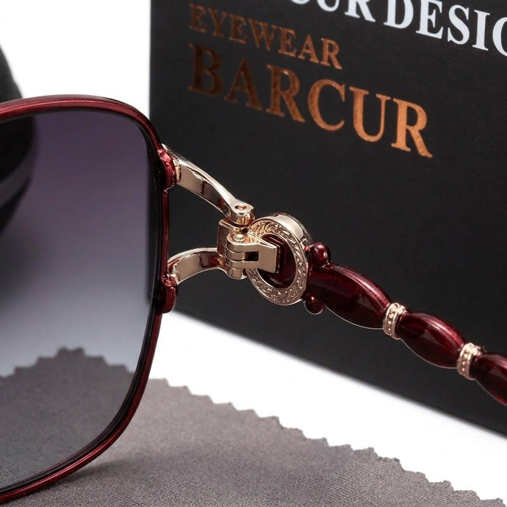 Macro close-up of beaded temple hinge and metallic detailing on dark red sunglasses